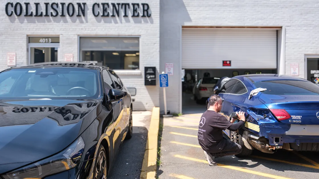 Vehicle repair technician working on a bumper sensor, illustrating crash avoidance repair costs and ADAS calibration