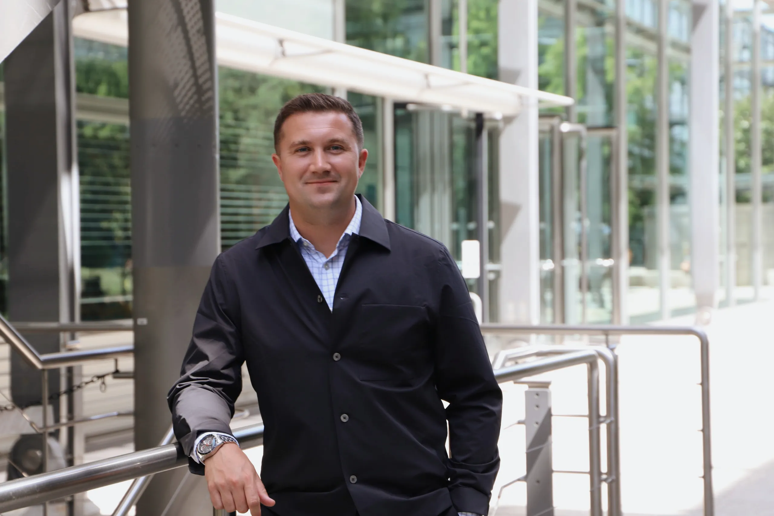 Lloyd Ker, CEO of Orthene Chemicals, leaning on a railing outside a glass-fronted building